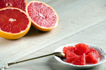 Slices of grapefruit on a plate, a spoon and a grapefruit