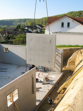 Bau eines Fertigkellers mit einer Betonwand hängend an einem Kran