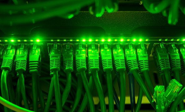 Close up of green network cables connected to switch glowing in the dark