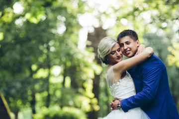 Fototapeta premium Beautiful wedding couple hugging in the park