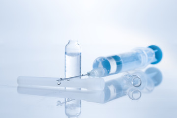 Medical syringe with injection solution drop. Toned image.