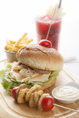 Delicious hamburger and french fries and onion rings on wooden b