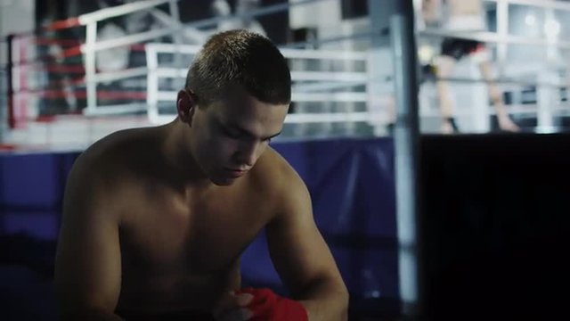 Male boxer wraps his hands with red handwrap before going to fight to the ring. Shot on RED Cinema Camera.