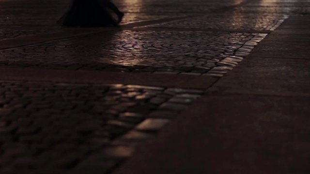View of asphalt in night city. Man and woman feets go on road. Camera on ground