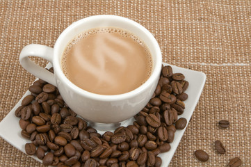 coffee and milk and saucer with grains on a background sacking