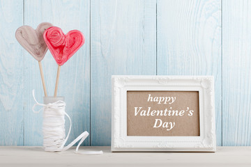 Valentine's Day heart shaped lollipop and white frame on blue wooden background
