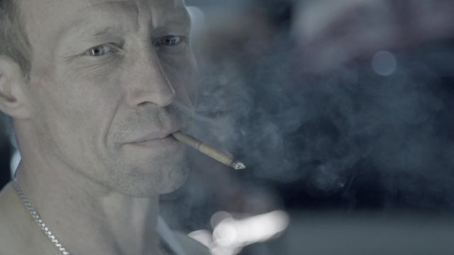 Portrait of a working auto mechanic smoking cigarette in garage in slow motion