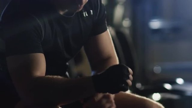 Male boxer wraps his hands with black handwrap before the fight training. Shot on RED Cinema Camera.