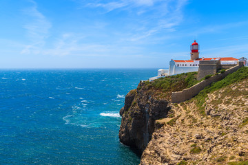 Fototapeta na wymiar Blue sea and lighthouse on top of cliff at Cabo Sao Vicente, Algarve region, Portugal