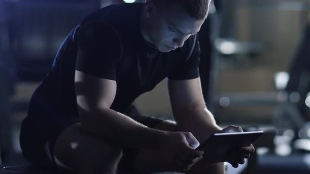 Handsome fit sporty man is using a tablet computer in the gym. Shot on RED Cinema Camera.