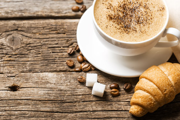 Close-up of coffee cup with roasted coffee beans on wooden backg