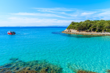 Fototapeta na wymiar Tourist boat cruising on turquoise sea water near Petit Sperone bay, Corsica island, France
