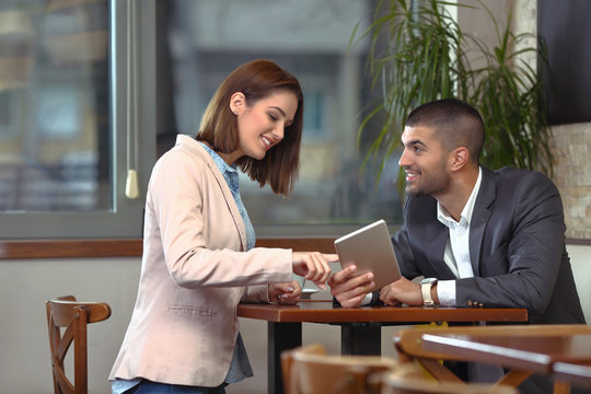 Two young business people using digital tablet on a meeting at coffee shop