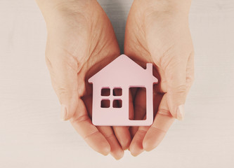 Female hands with model of house on light background