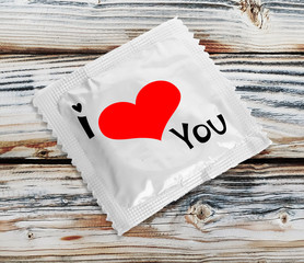 Condom with text I love you on wooden table