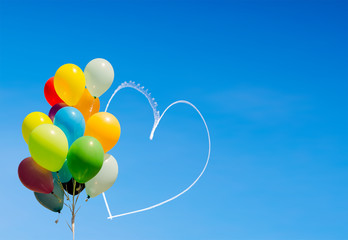 Fototapeta na wymiar Colorful balloons and heart written in the sky by aircraft