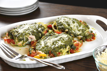 Tasty baked chicken breasts are covered with basil pesto sauce, fresh cherry tomatoes, yellow bell peppers and topped with melted parmesan cheese.