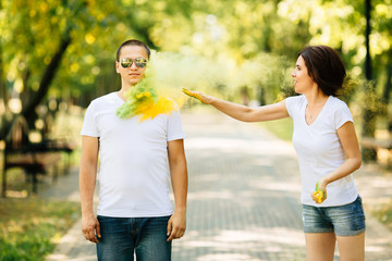 Young and beautiful, hipster couple playing in the park on holi color festival with colour paint powder.