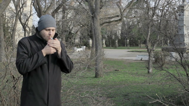 Young guy smokes at a park