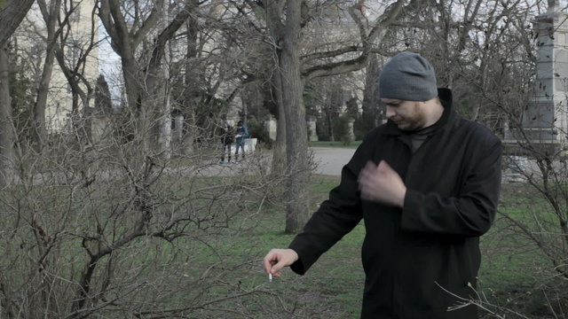 Young guy smokes at a park