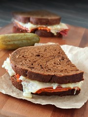 Reuben sandwiches with corned beef and melted Swiss cheese on wood