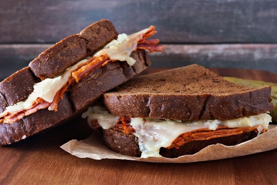 Reuben Sandwiches Stacked With Corned Beef And Melted Swiss Cheese With Rustic Wood Background