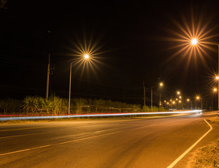 Fototapeta na wymiar Night Road at suburban with the light trails car - Night transportation and ray of a star 