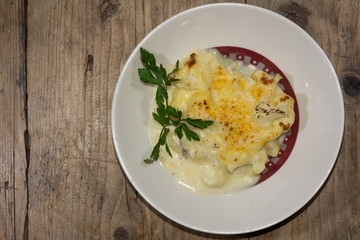 Cauliflower cheese prepared by French chef, from above. A classic vegetable side dish presented on a white plate
