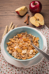 Healthy breakfast with muesli, red apple and cinnamon on rustic
