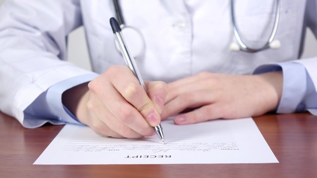 Medical diagnose, doctor with stethoscope continue writing a receipt for patience
