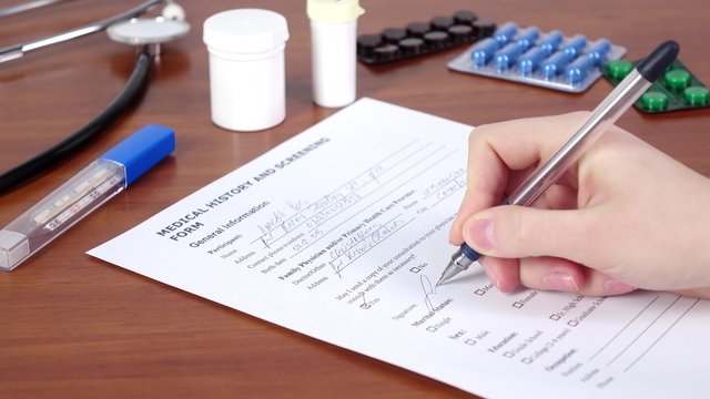 Doctor continue writing a medical history and screening form of the patient