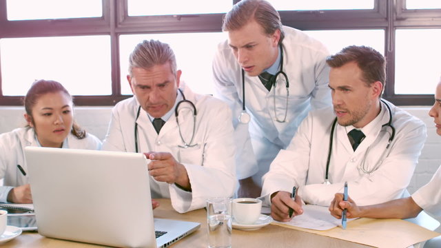 Medical team talking together while looking laptop