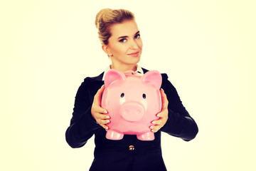 Happy businesswoman saving money in piggybank