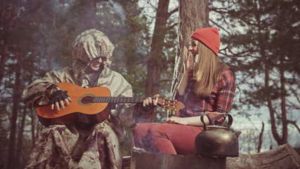 Maniac dressed in a dirty bloody raincoat is playing guitar to the victim. Artistic toning.