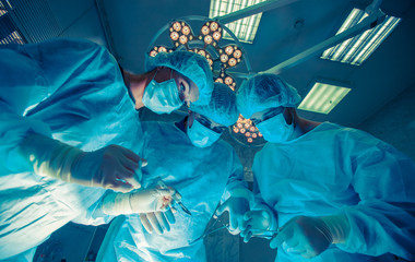 Surgeons standing above of the patient before surgery