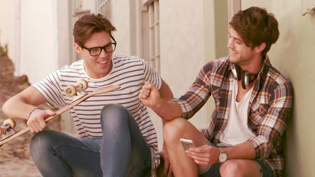 Hipster friends sitting together while holding skateboard