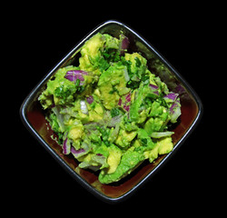 Guacamole in a bowl isolated on black background.
