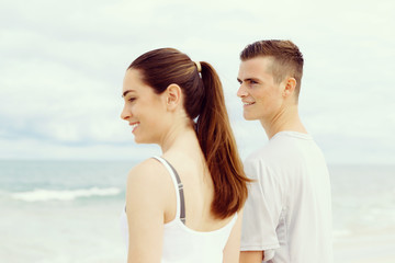 Young couple looking thoughtful while standing next to each other on beach