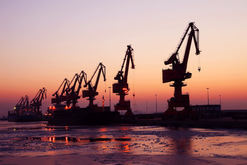 Obraz premium In the evening, the silhouette of port cranes