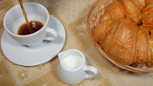 Pouring Coffee into Cup with Croissant