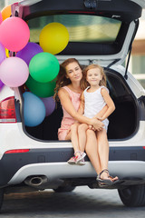Fototapeta na wymiar Mom and daughter in a car with balloons