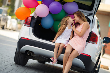 Mom and daughter in a car with balloons