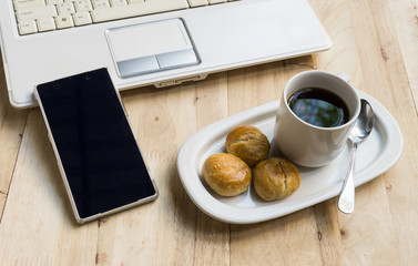 cup of coffee and laptop on the wood texture background