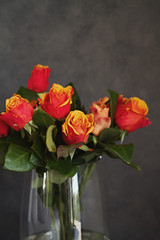 Close up of orange and yellow roses in glass vase