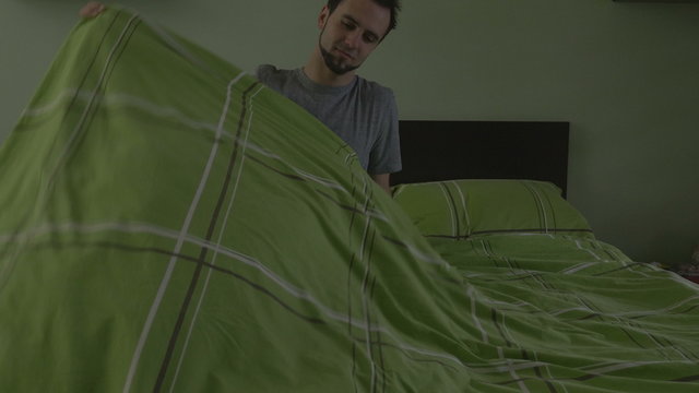 Young handsome man pulling the blanket and sleeping