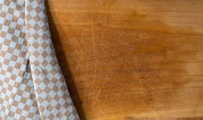 Cutting Board Covered with Tablecloth / Used wooden cutting board partially covered with a brown and white checkered tablecloth