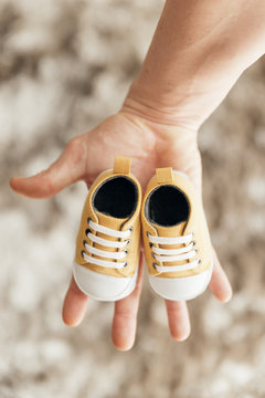 Lovely dad holding a pair of baby shoes.