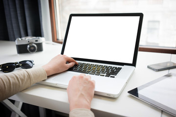 Woman using a laptop naxt to a window with tablet pc and smartph