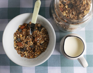 Healthy eating, muesli and milk for breakfast. Muesli in a bowl, milk and a jar with muesli, photo taken from the top.
