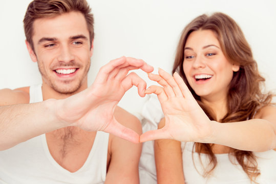Happy romantic couple in love gesturing a heart with fingers